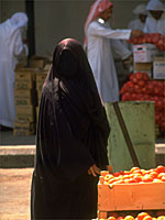 A woman wearing a chador shops for peaches in Saudi Arabia.